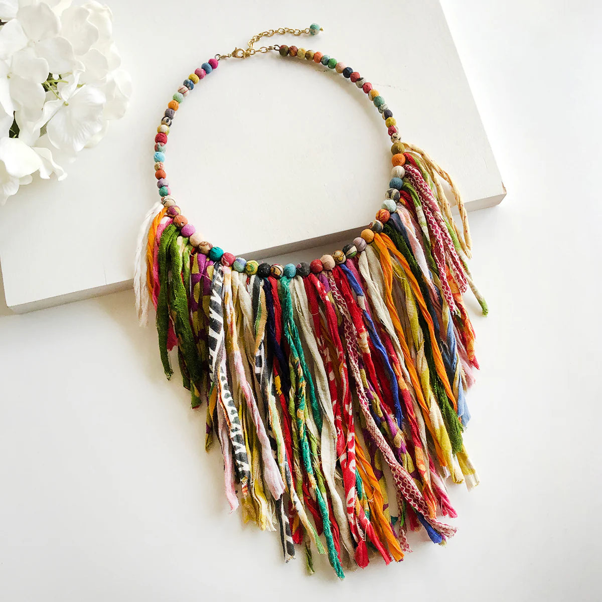 A colourful necklace with fabric beads and a fringe of multicoloured fabric tassels.