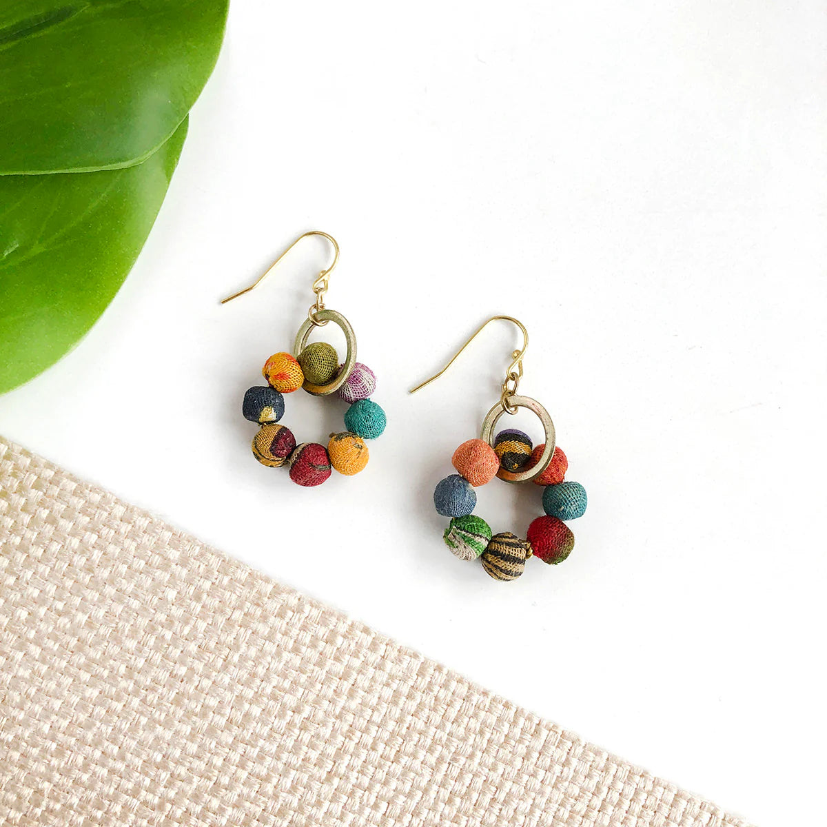 A pair of colourful beaded earrings with gold hoops.