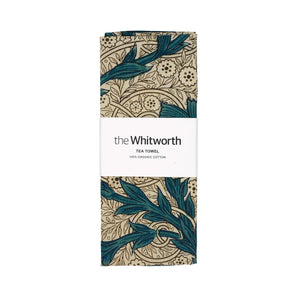 Tea towel folded up with a belly band with the Whitworth branding placed around. The tea towel features a floral design called Carnation by Kate Faulkner