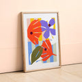 Print of digital illustration by Kate Moorhouse of colourful flowers - placed in an ash frame leant against a peach wall