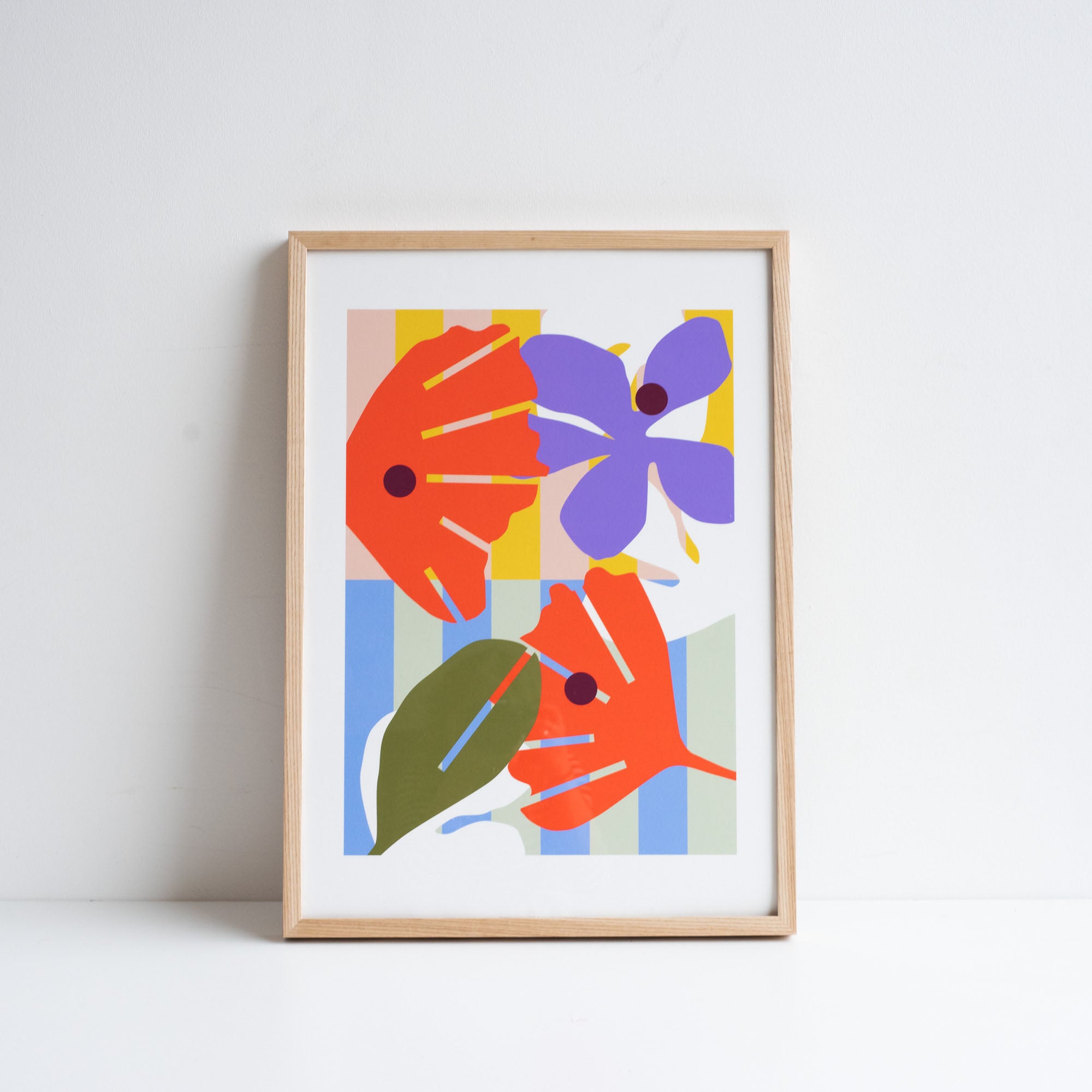 Print of digital illustration by Kate Moorhouse of colourful flowers - placed in an ash frame leant against a white wall