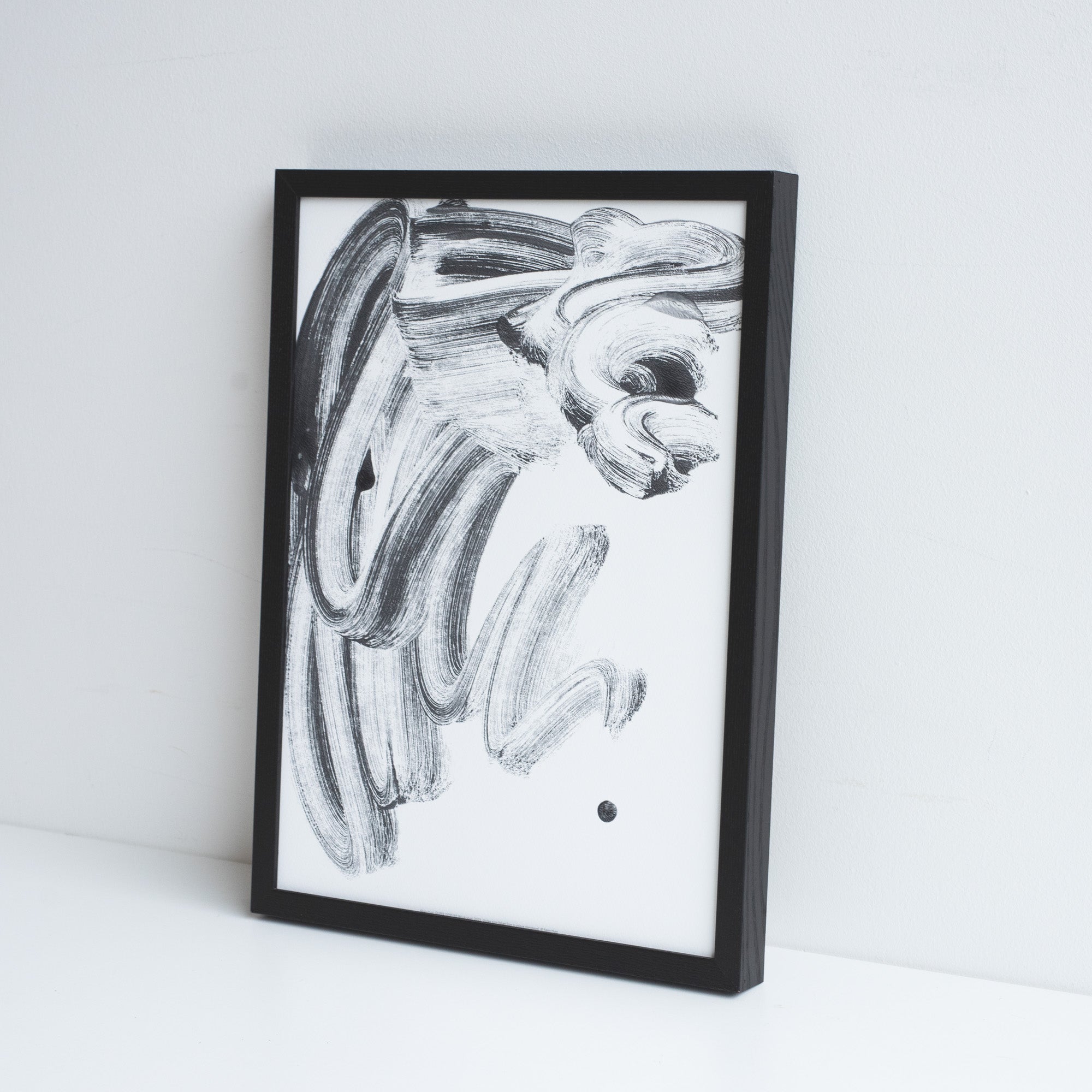 Printed reproduction of a unique Monotype by Kevin Hunt, placed in a black frame leaning against a white wall.
