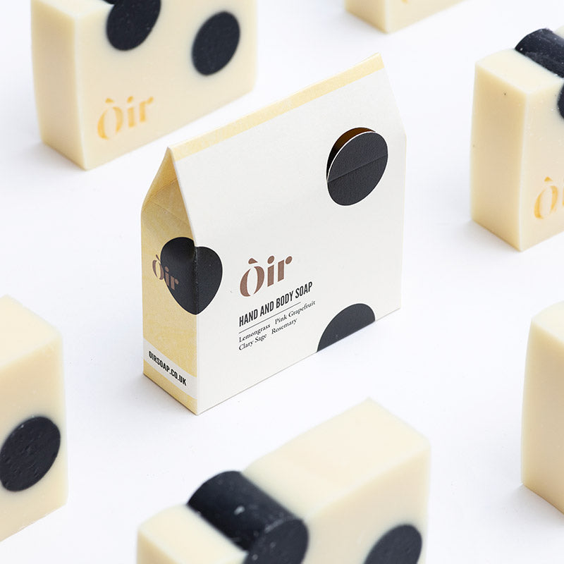 The image shows packaging for hand and body soap. It has a cream and black circles design. 