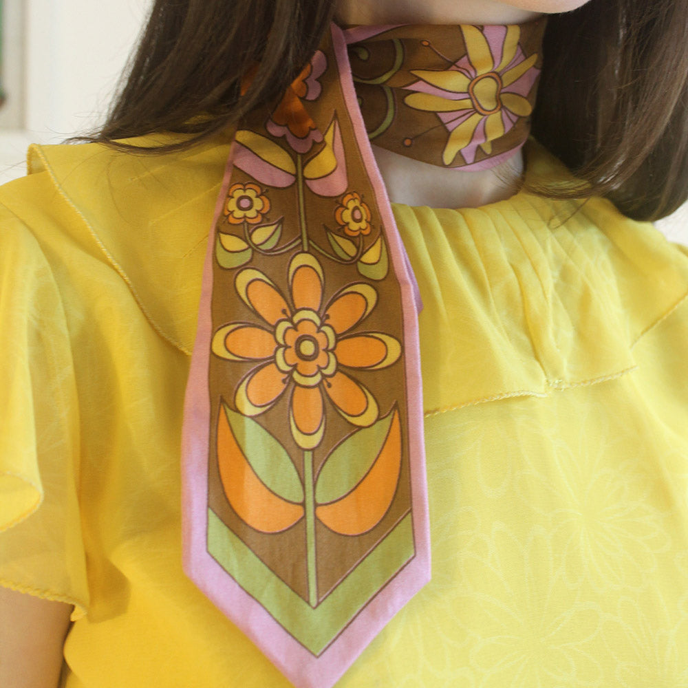 Person wearing a floral patterned scarf with a yellow shirt