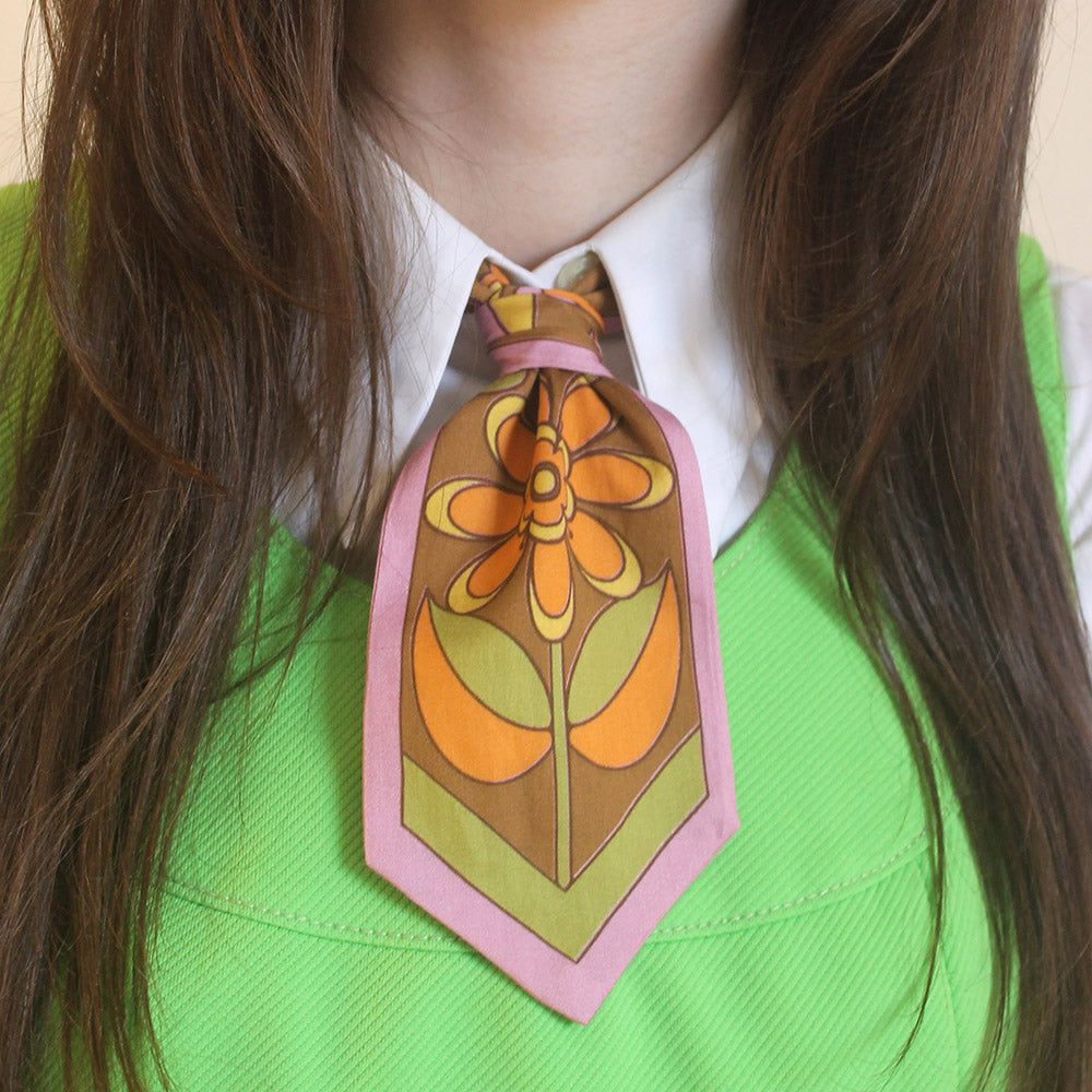 Person wearing a floral scarf with a green shirt and white collar.
