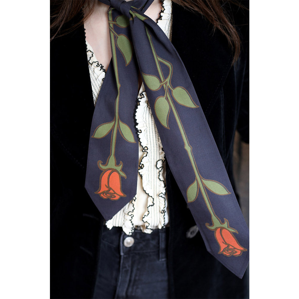 Person wearing a tie shaped scarf around their neck with roses print.