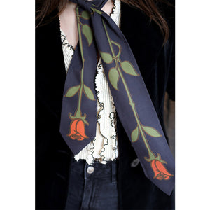 Person wearing a tie shaped scarf around their neck with roses print.