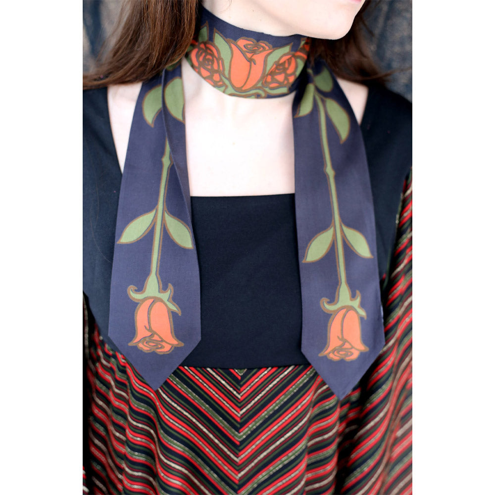 Person wearing a tie shaped scarf around their neck with roses print.