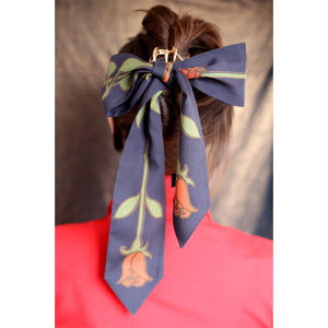 Person wearing a tie shaped scarf as a hair band with roses print.