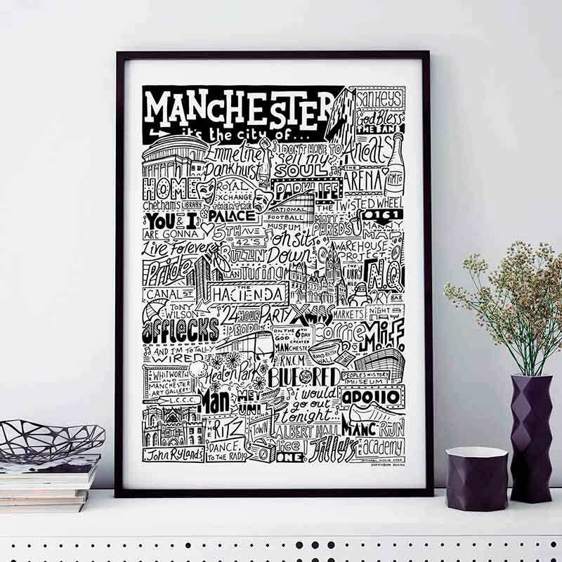 A black and white illustration celebrating Manchester's cultural landmarks and music scene, featuring iconic venues, band names, and local references. Placed in a black frame on a white surface.