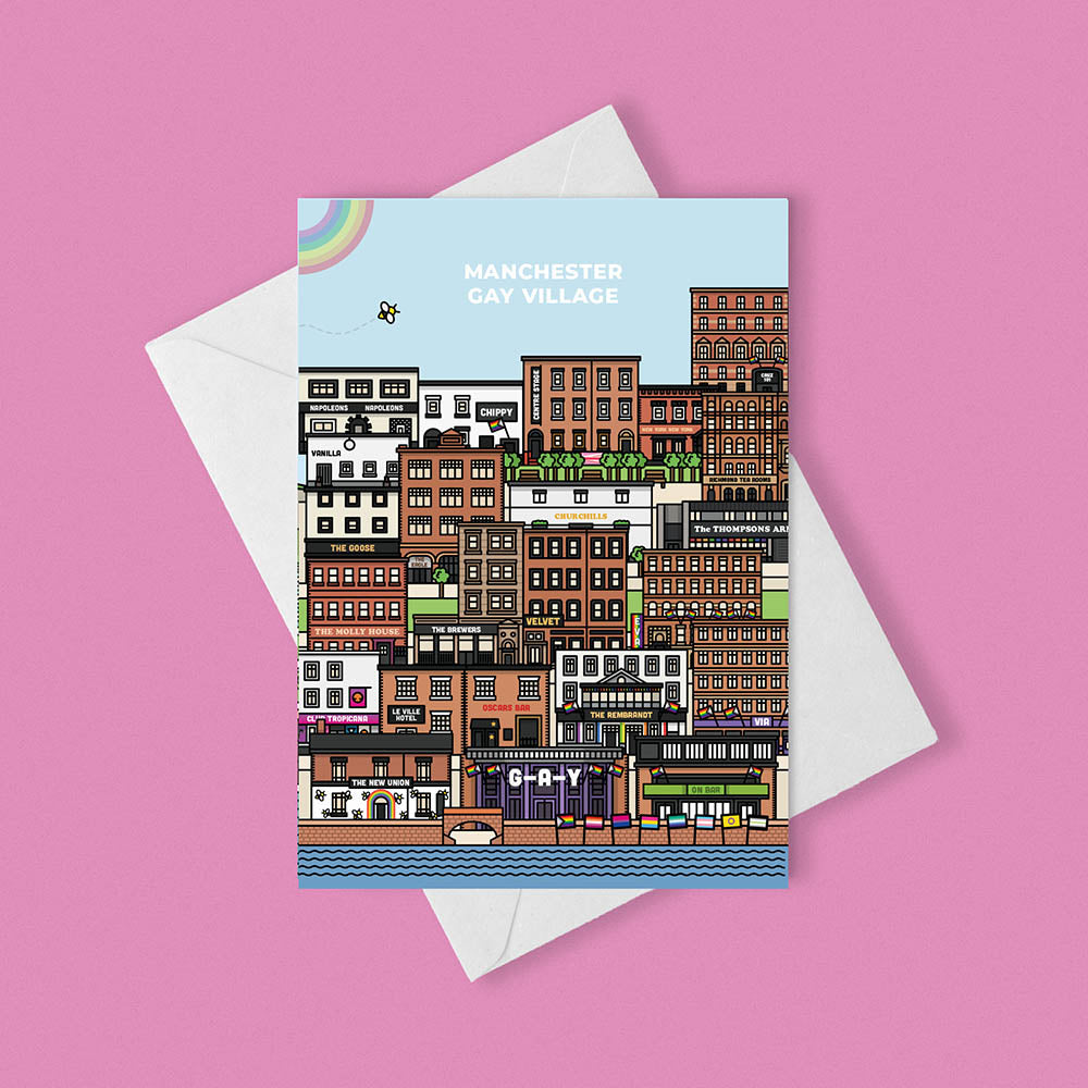 A greetings card featuring an illustration of various buildings and landmarks from Manchester's Gay Village. The card is placed on top of a white envelope against a pink background. 