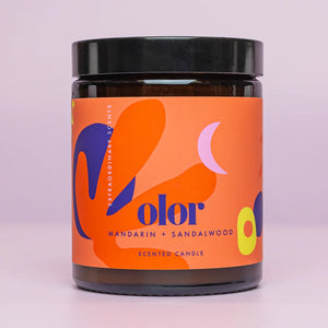 Candle in Jar with Olor orange branding. Pink background.
