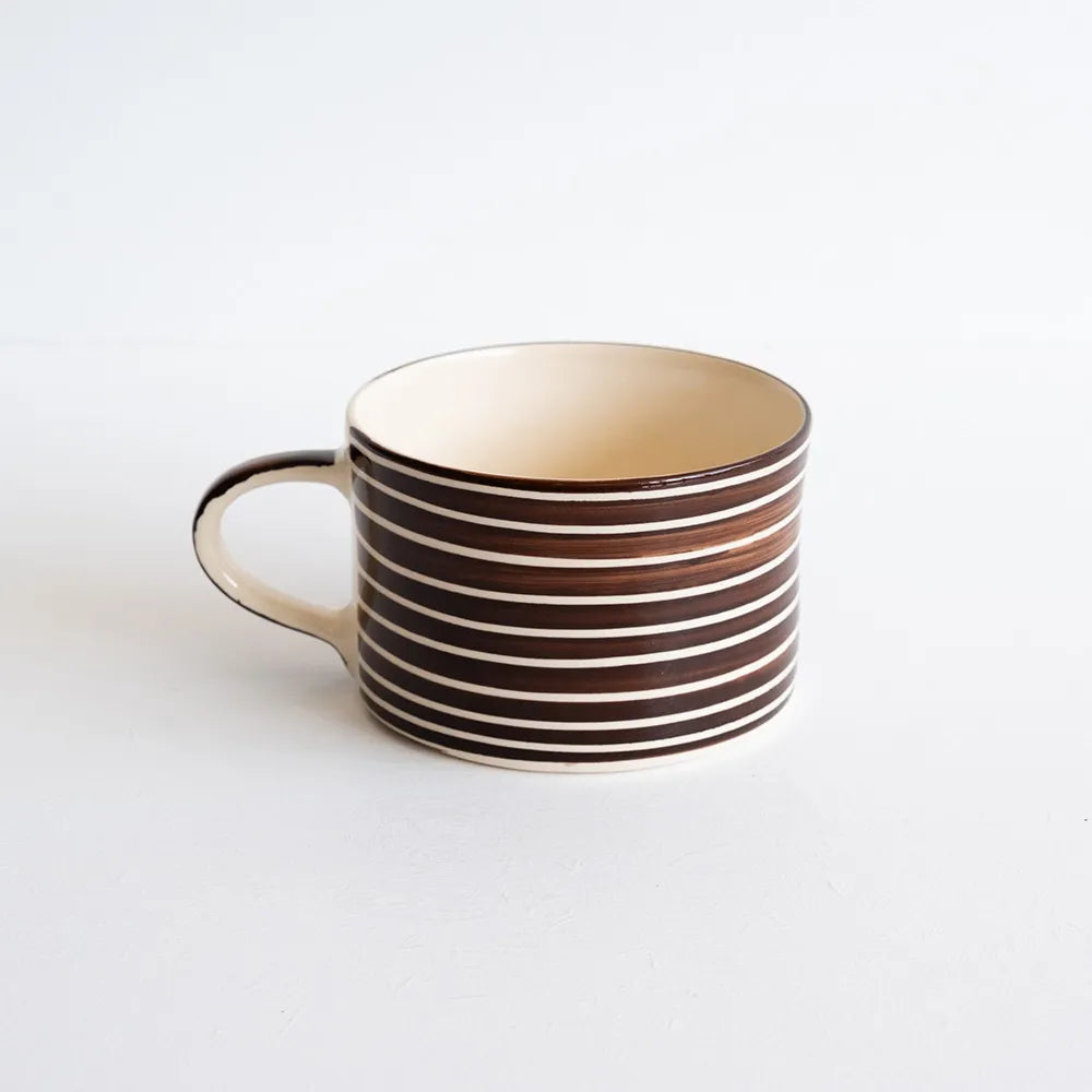 A ceramic mug with brown and white striped against a white backdrop.