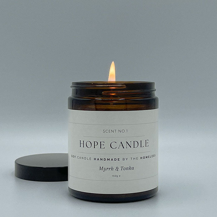 Lit glass candle with a white label