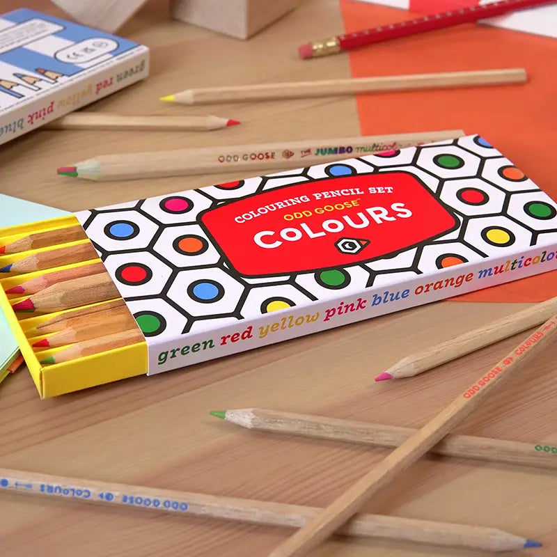 Box of colouring pencils on a wooden surface with pencils scattered around.