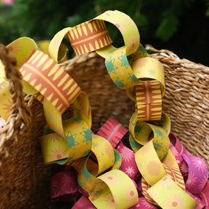 A photo of a woven basket filled with paper chains. The chains are in various colours and patterns, including yellow, pink, red, and green.