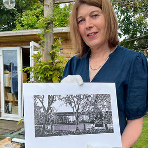 A photograph of artist Paula Payne holding one of the prints.