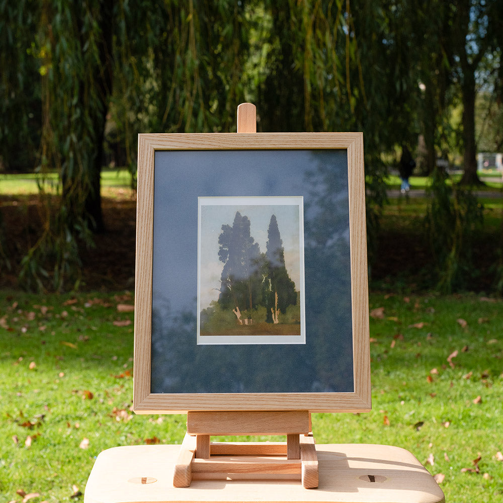 Wooden easel with a framed picture on a grassy outdoor setting