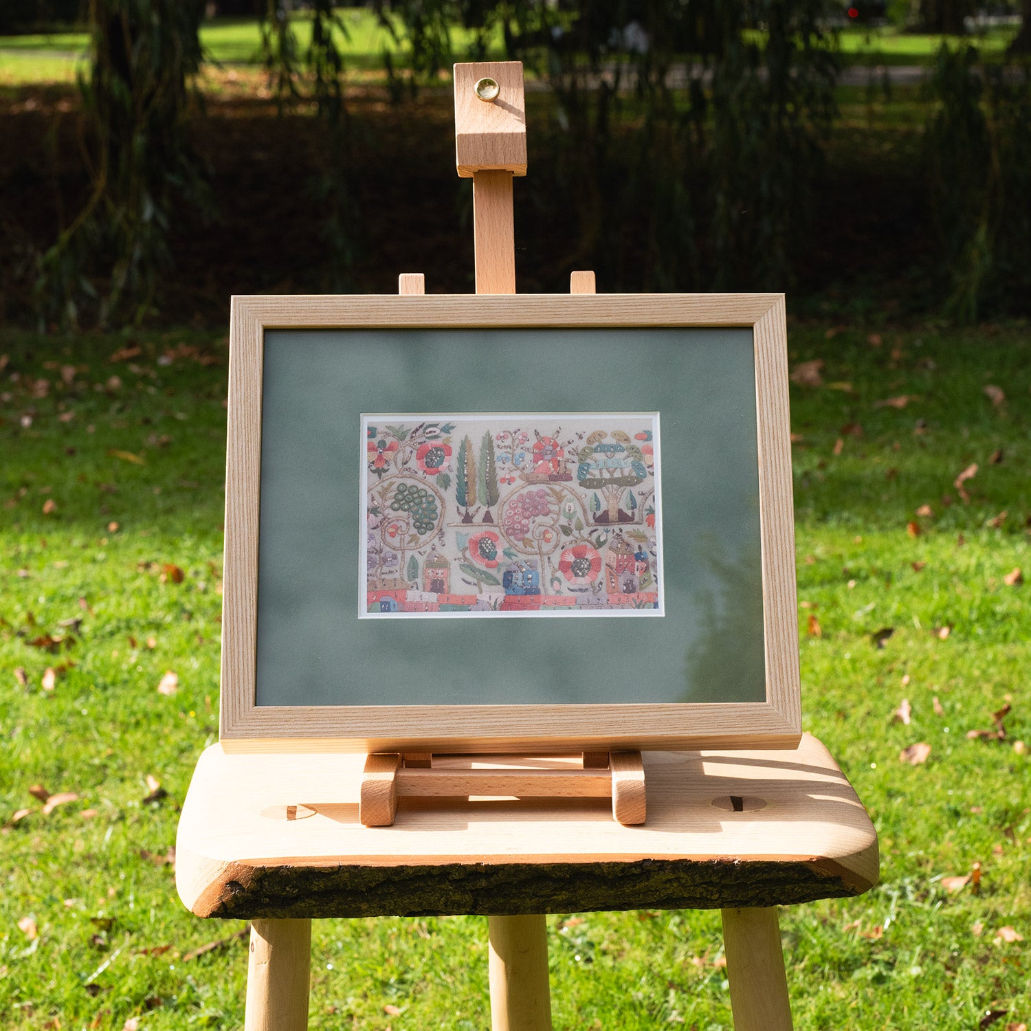 Wooden easel with a framed artwork on a grassy background