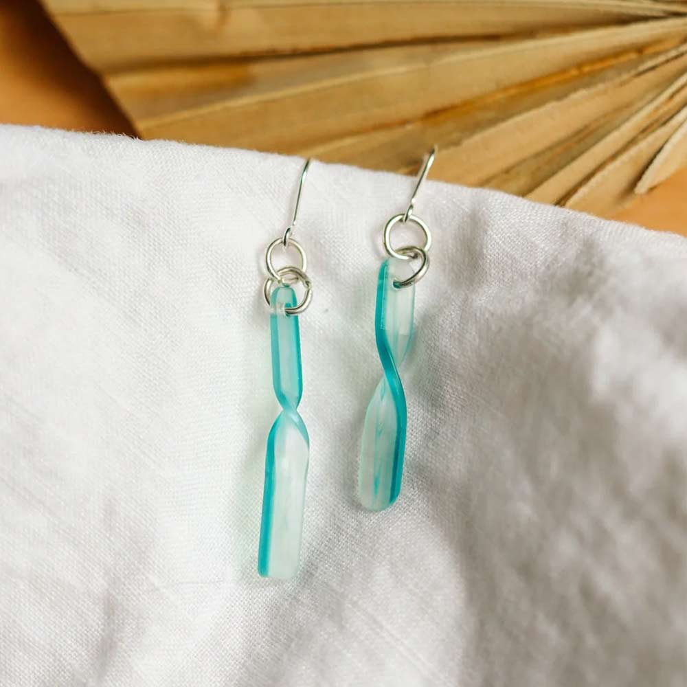 Sea blue twisted earrings photographed on off-white cloth