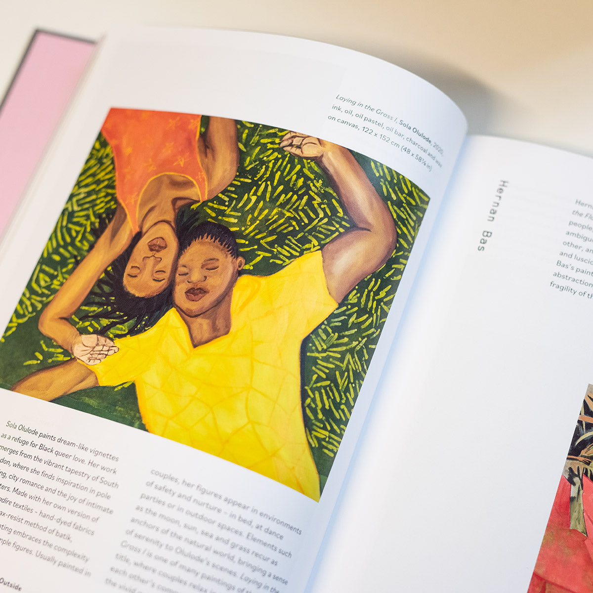 Inside page of Queer Art book with a painting of two people laying on grass by Hernan Bas