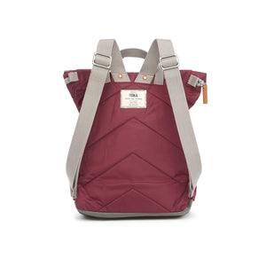 Reverse of maroon backpack with grey stripes. ROKA's logo is stitched into the fabric,