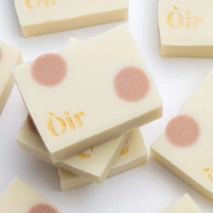Three creamy white bars of soap with light pink spots and the word "Òir" printed on them in gold, stacked on top of each other.