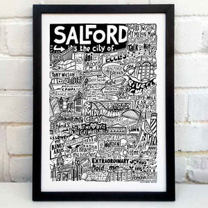 A black and white illustration celebrating Salford's cultural landmarks and music scene, featuring iconic venues, band names, and local references. Placed in a black frame in front of a white wall.