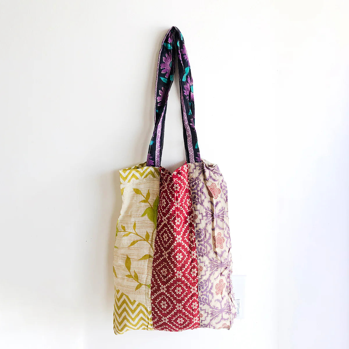 A colourful patchwork tote bag with long handles.