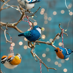 Felt birds in various colours hanging on a Christmas tree.