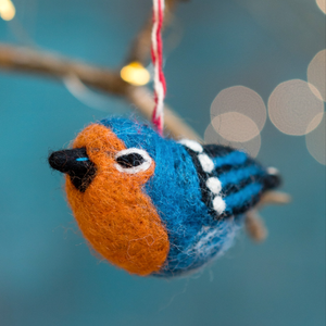 Felt bird in orange and blue colours hanging on a Christmas tree.