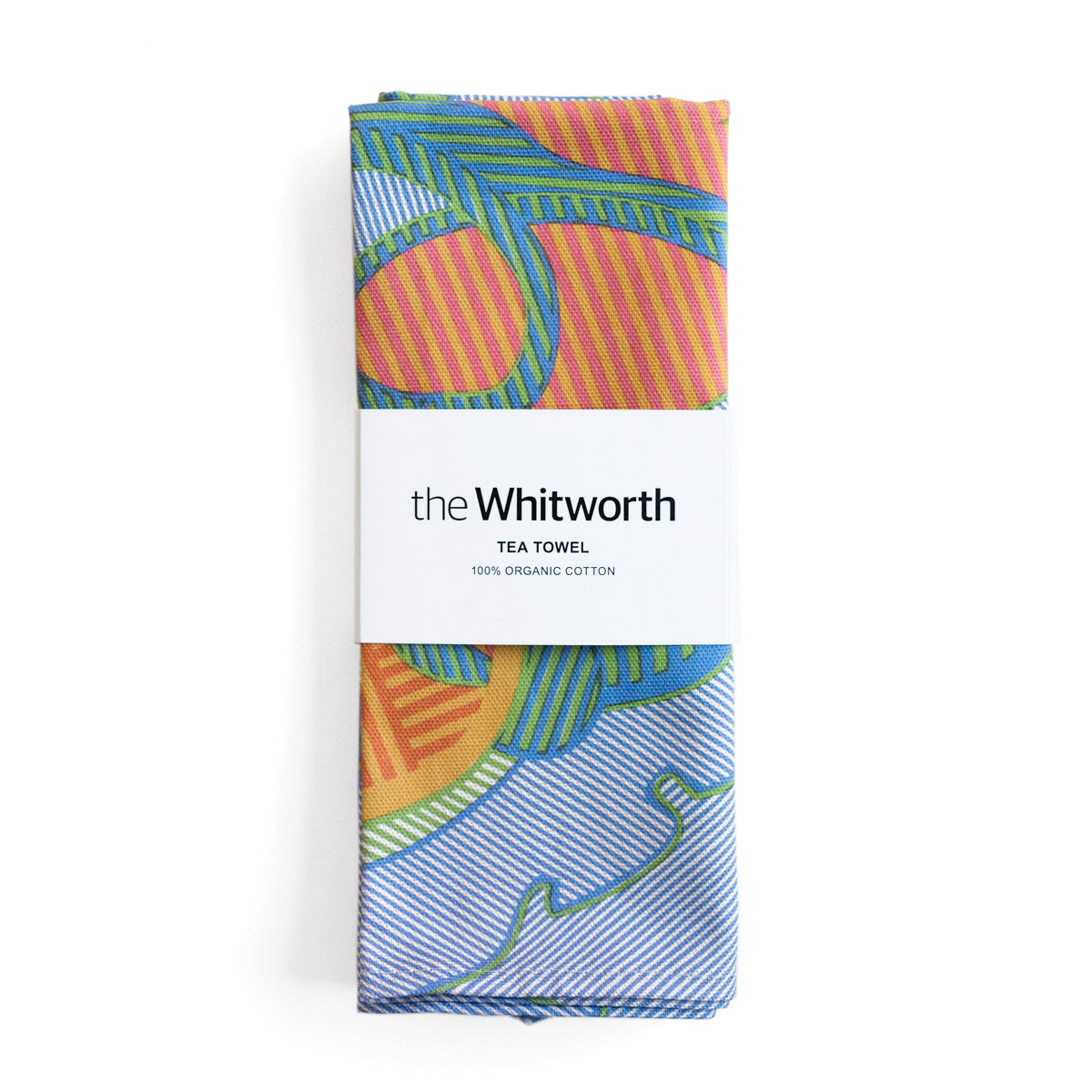 Tea towel with a vibrant pattern featuring blue, orange, and pink shapes. This pattern is a detail of a design by Shirley Craven. Belly band around the tea towel with the Whitworth logo.