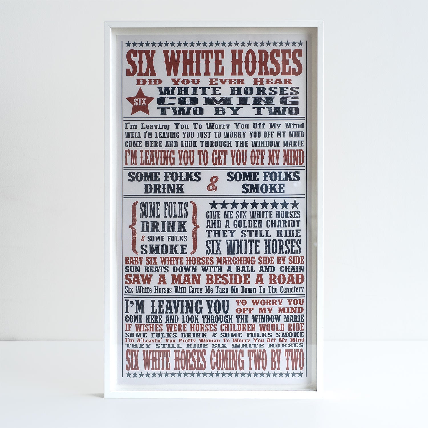 Photograph of limited edition print featuring typography of song lyrics in red and black font. White frame. White background.