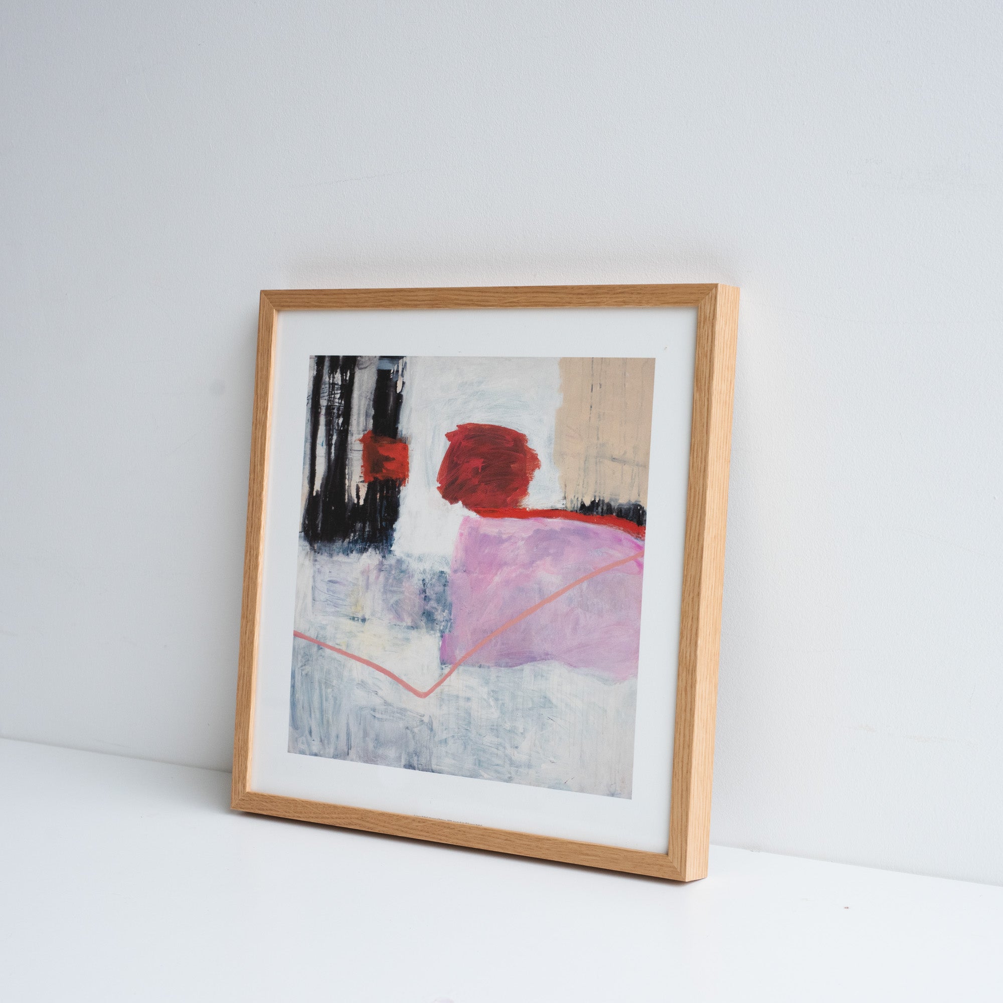 Reproduction of an abstract painting by Suzanne Bethell in an ash frame, rested against a white wall.