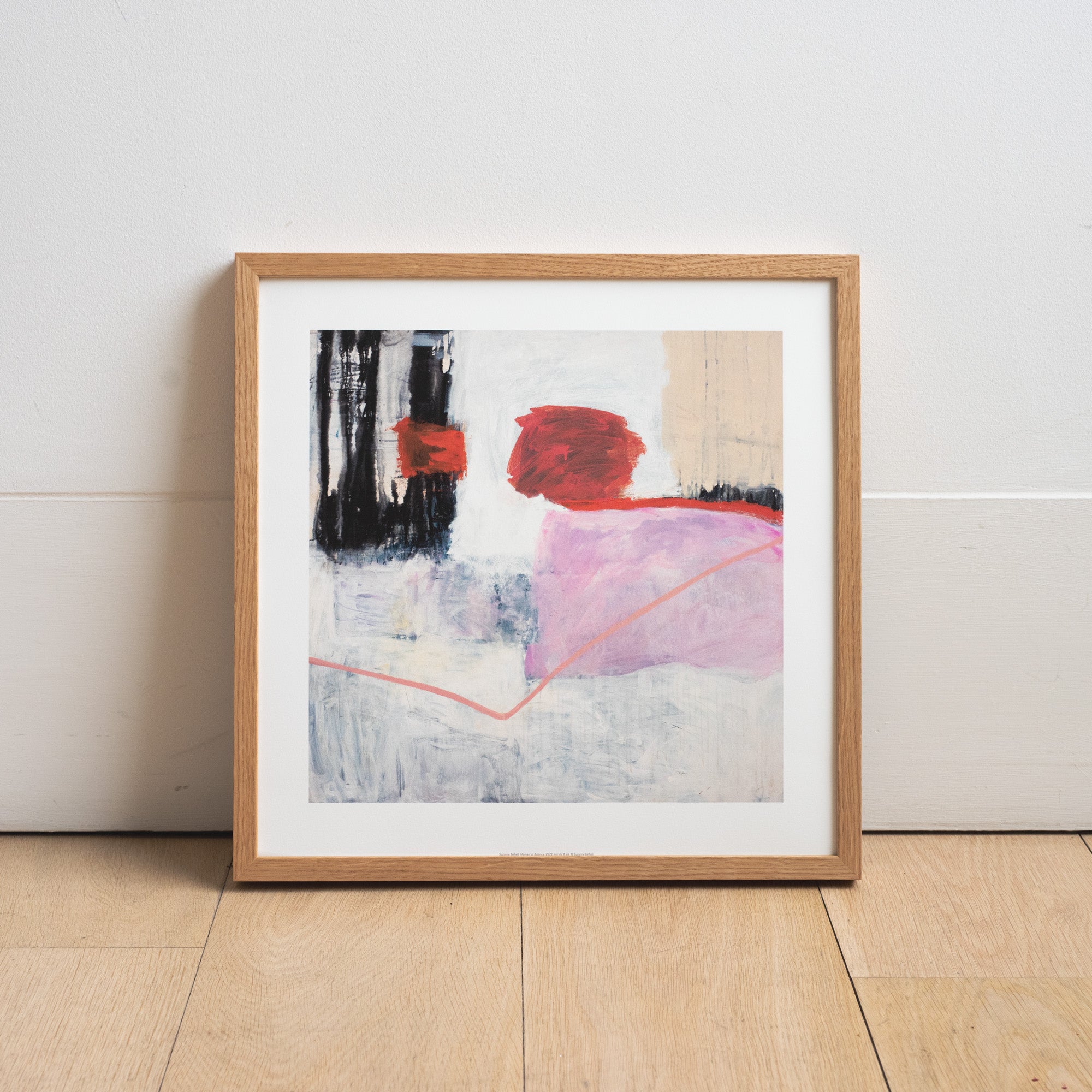 Reproduction of an abstract painting by Suzanne Bethell in an ash frame, rested against a white wall.