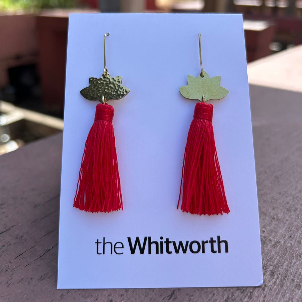 Red tassel earrings on a 'the Whitworth' branded card.