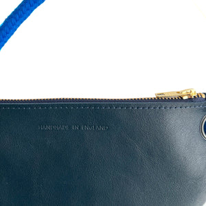 Detail of navy leather bag featuring gold zip and 'Handmade in England' embossed lettering.