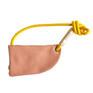 A pink leather cross body bag with a yellow rope handle.