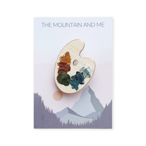 Brooch in the shape of a paint palette placed on a Mountain and Me Branded backing card