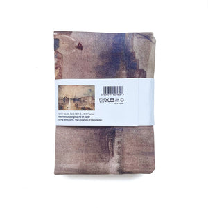 Folded fabric tea towel with a label on a white background