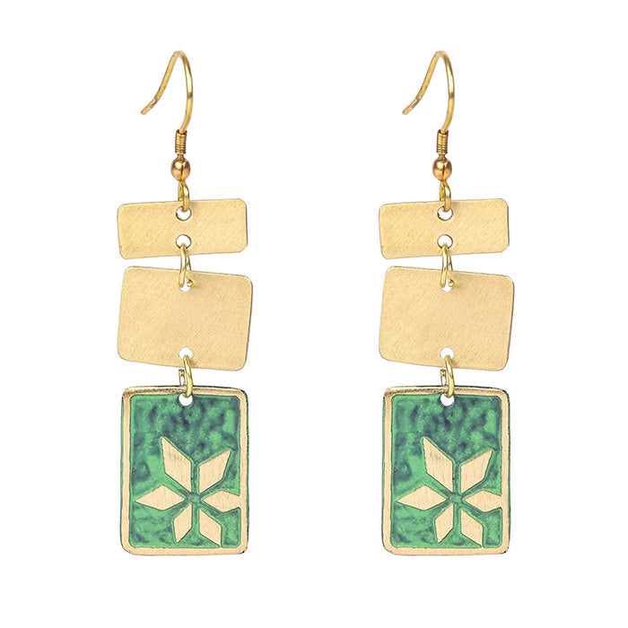 Pair of earrings against white background. Each earring has a hook fastening and is split into 3 shapes. The top two are gold rectangular and the bottom is green rectangle with geometric flower brass inprinted.