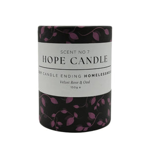 A black glass candle jar with a white label featuring pink vines.