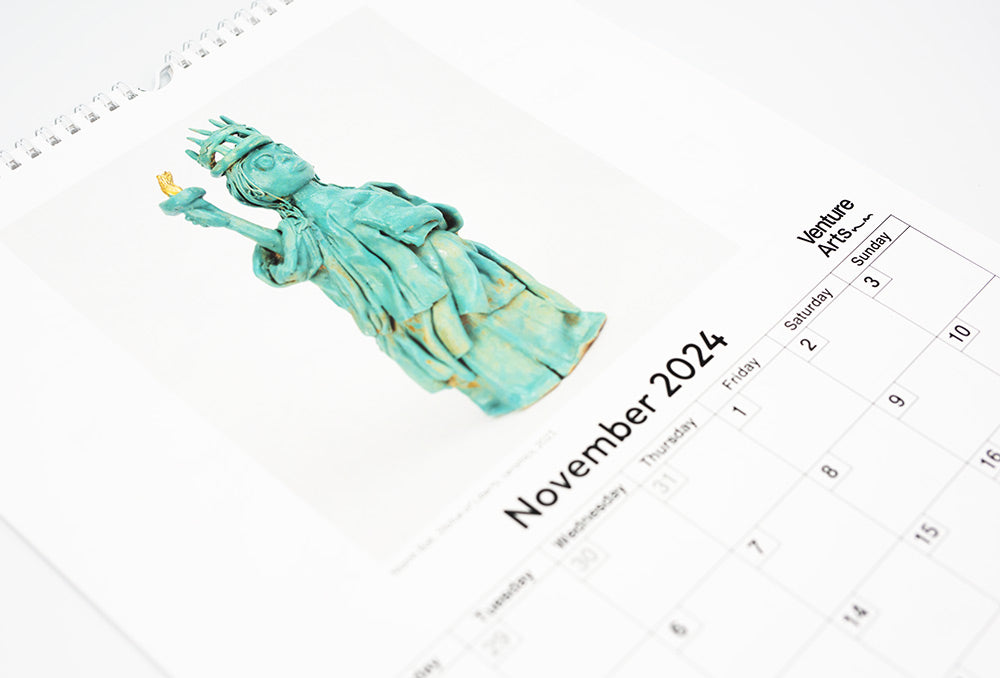 A close up of the November page of the calendar featuring a ceramic reproduction of the statue of liberty