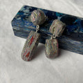 Pair of earrings with marbled design on a textured surface
