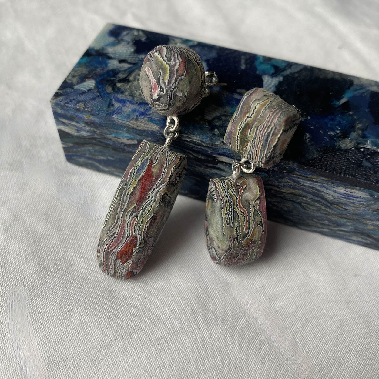 Pair of earrings with marbled design on a textured surface