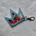 Crown shaped keyring with floral design on a grey fabric background