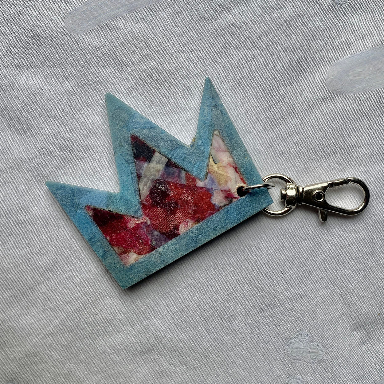 Crown shaped keyring with floral design on a grey fabric background