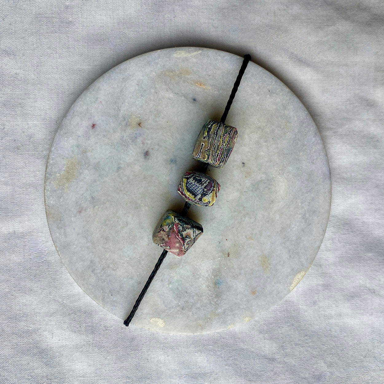 Necklace with three marbled stone-looking beads on circular marble surface