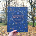 A person holding a blue cookbook in front of the Whitworth Park