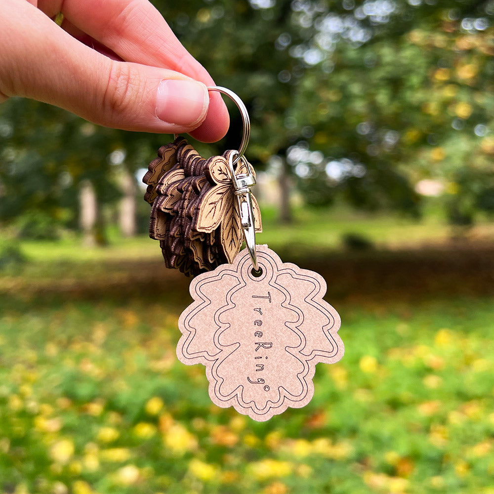 Keychain with tree-themed tags held by a hand against a blurred natural background